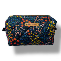 Trousse de voyages fond sombre avec des pites fleurs multicolores et logo tatamo en cuir embossé