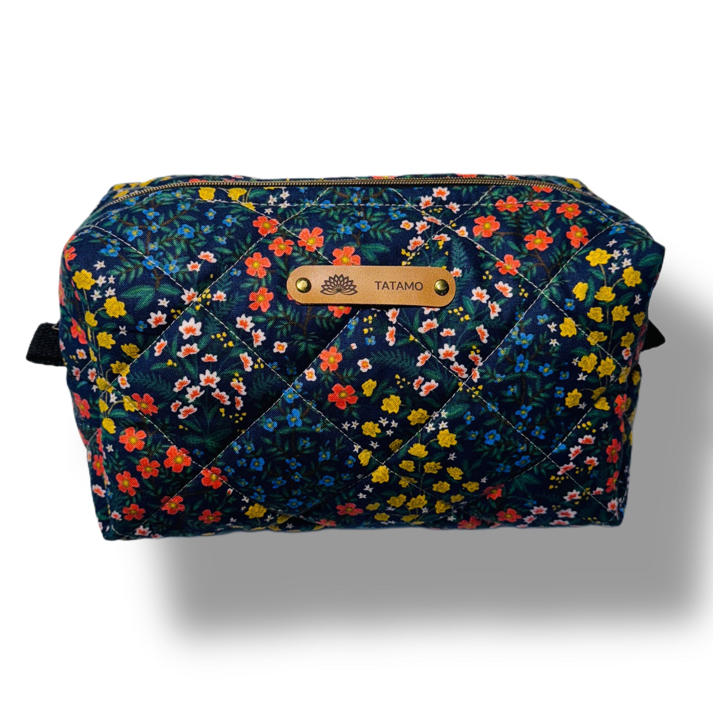 Trousse de voyages fond sombre avec des pites fleurs multicolores et logo tatamo en cuir embossé